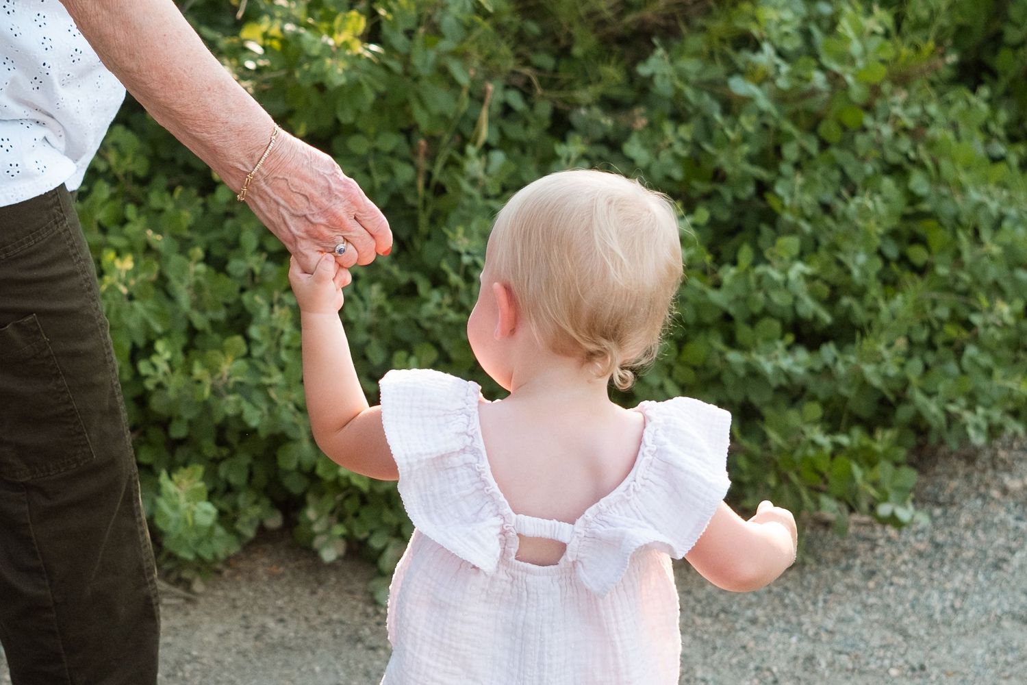 Close up of grandmother hold the hand of granddaughter on a summer day at a Denver park.