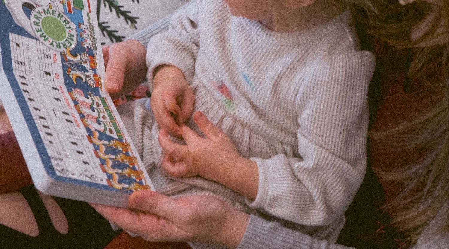 Close up of Mother reading Christmas book to toddler.