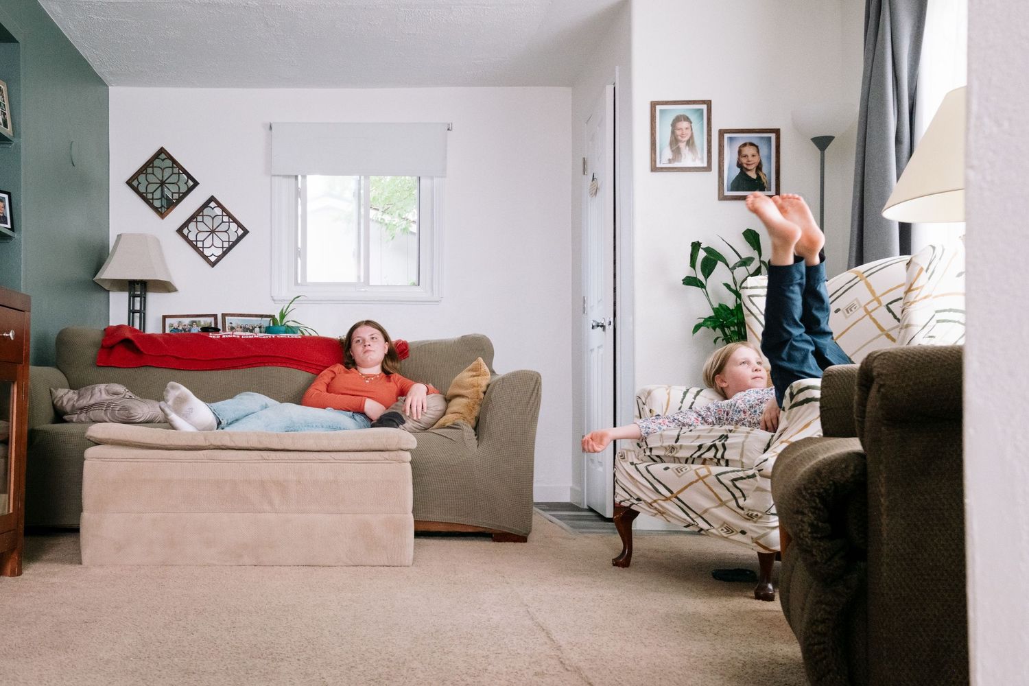 Sisters lounging in living room during documentary style in home family photography session.