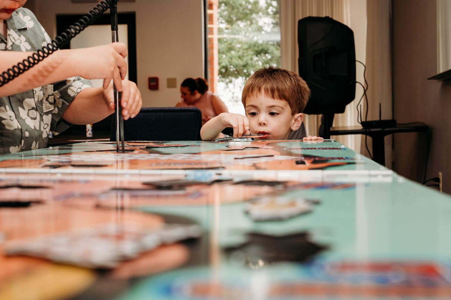 Young boy peering over life size game of operation at Grandmother's birthday party.