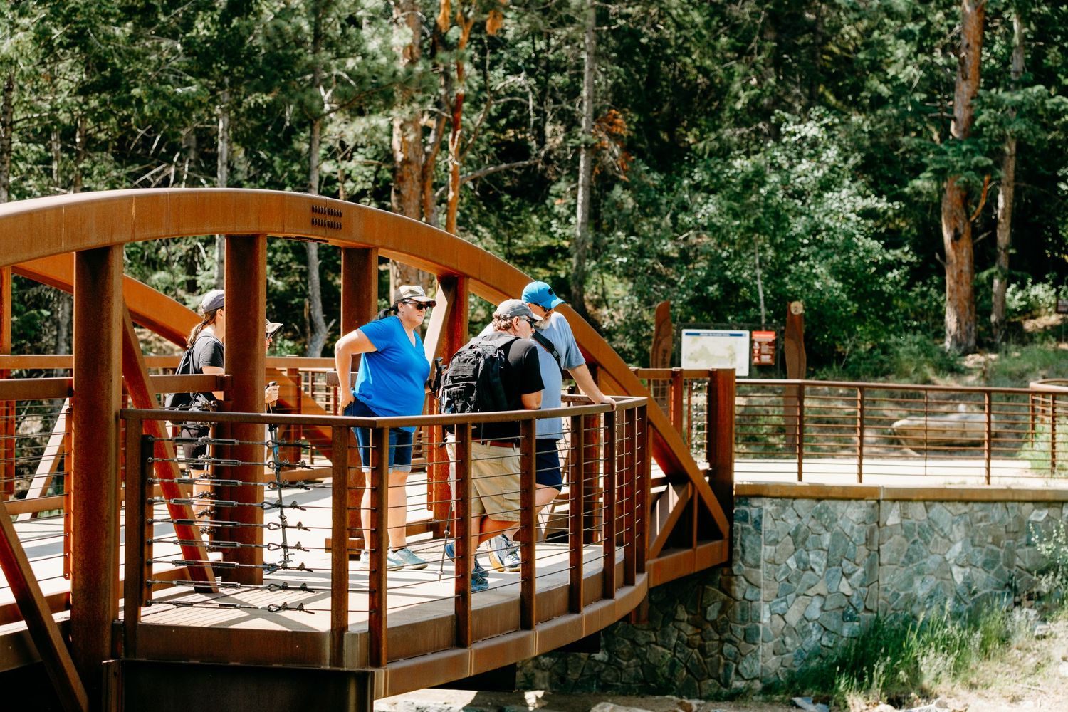 Several adults standing on a bridge overlooking Clear Creek River.