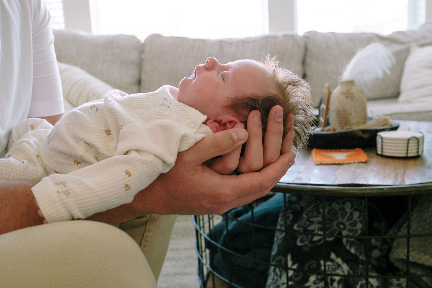 Father holding newborn in his hands, newborn sleeping.