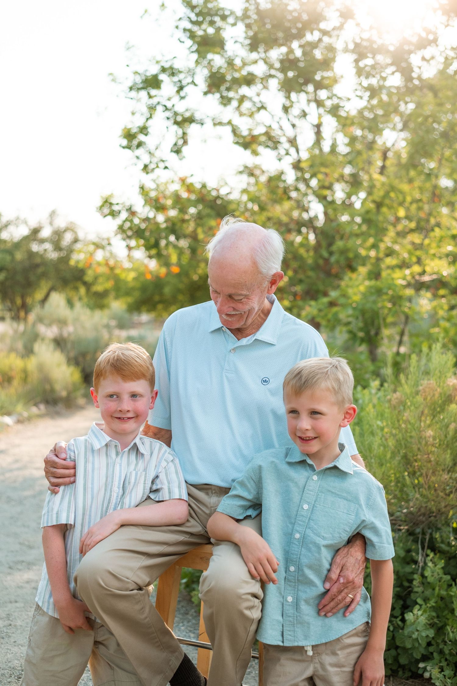 Grandfather posing with two grandsons on a summer day at a Denver park.