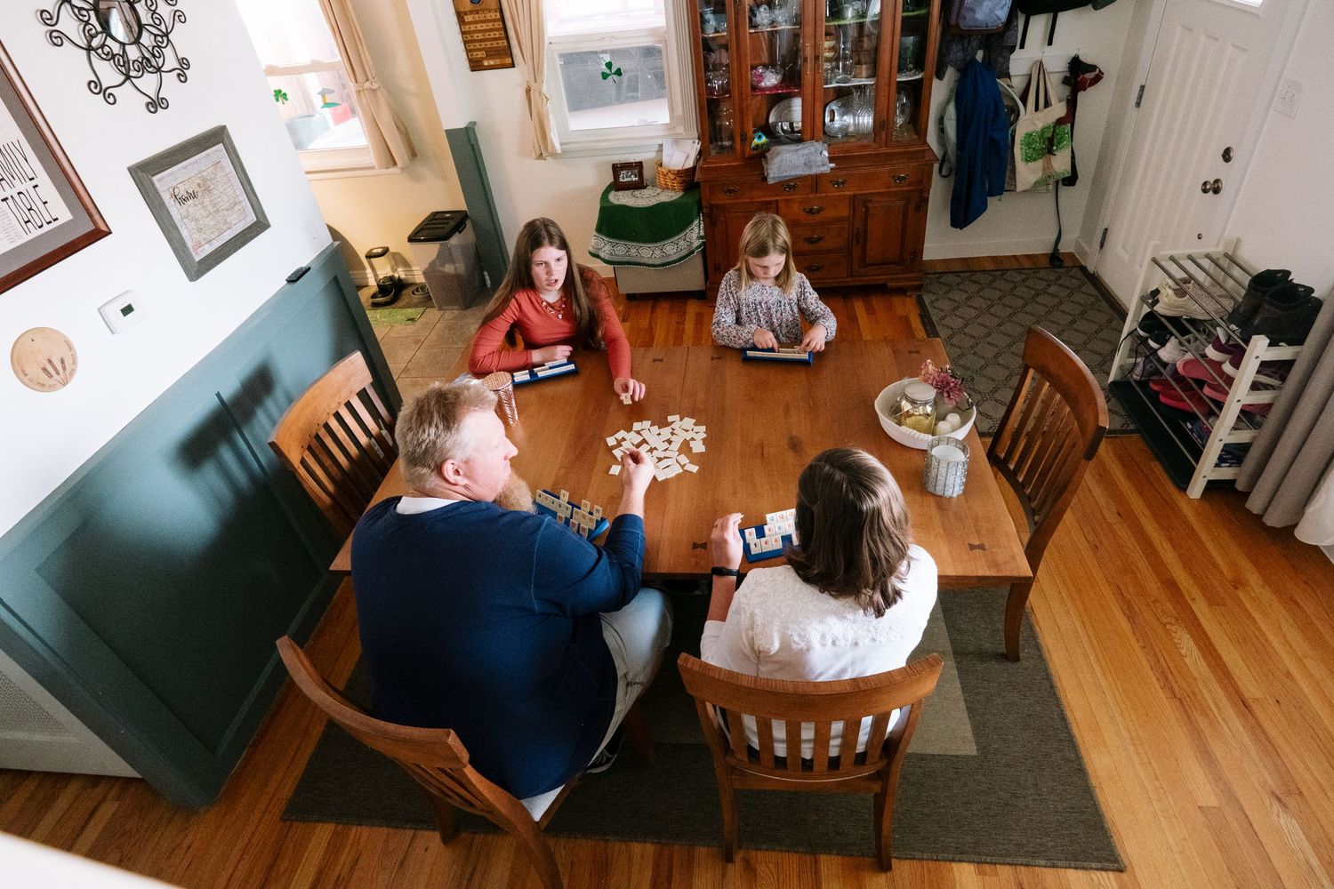 Overhead view of family of four playing game at dining room table in Denver home.