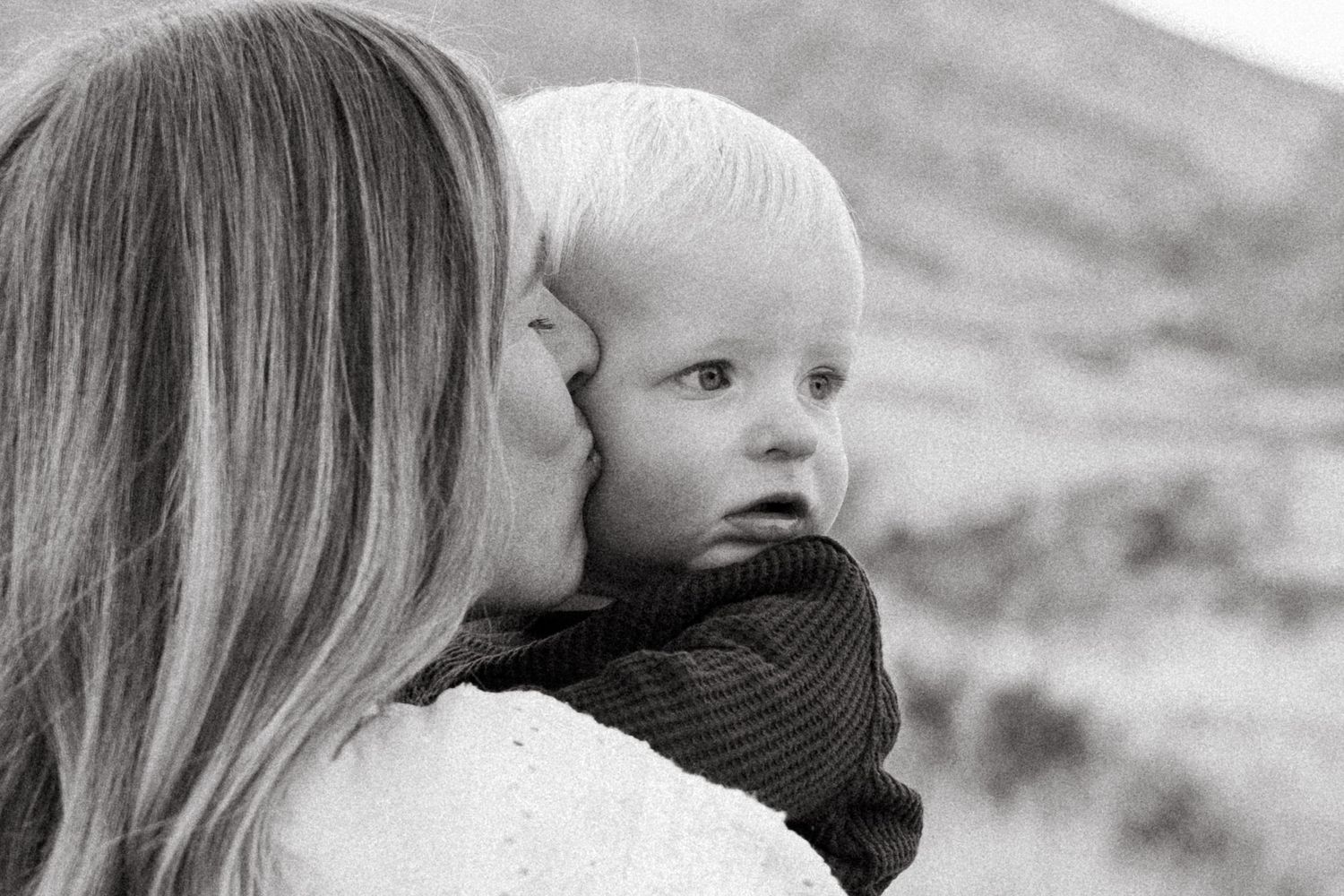Mother kissing the temple of one year old son.