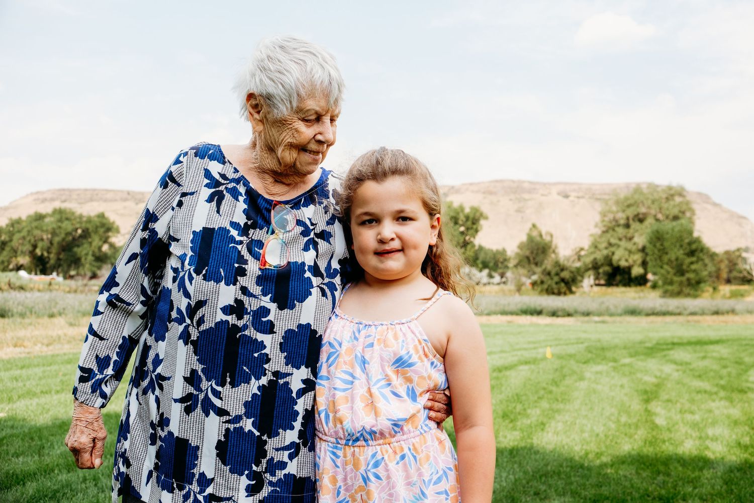 Grandmother peering down at granddaughter lovingly, foothills in background.
