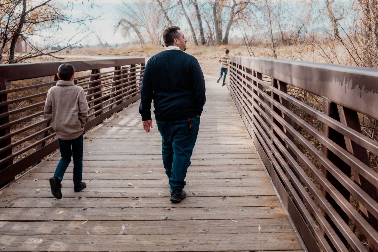 Father walking on bridge with two songs.