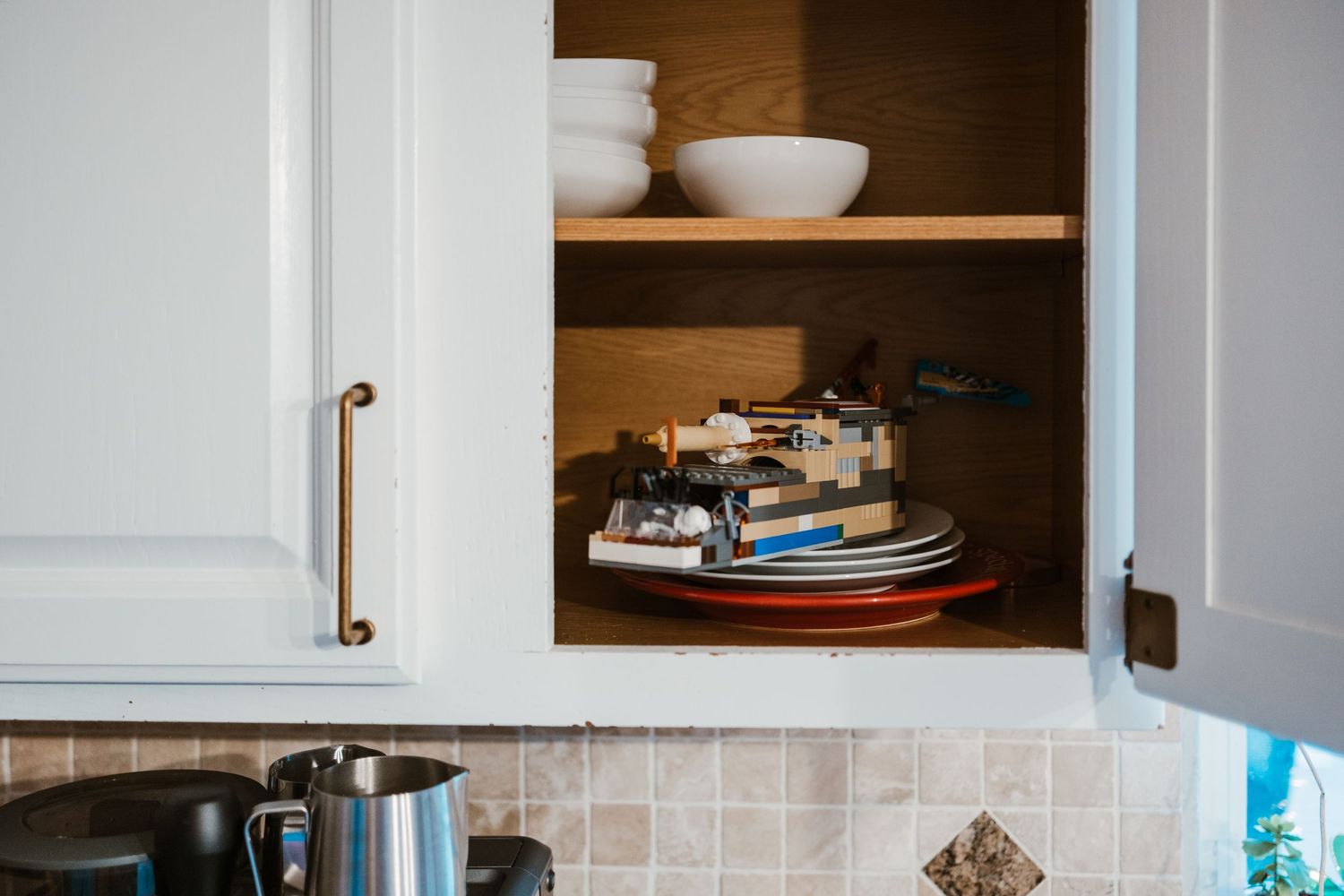 Legos sitting atop plates in cabinet.
