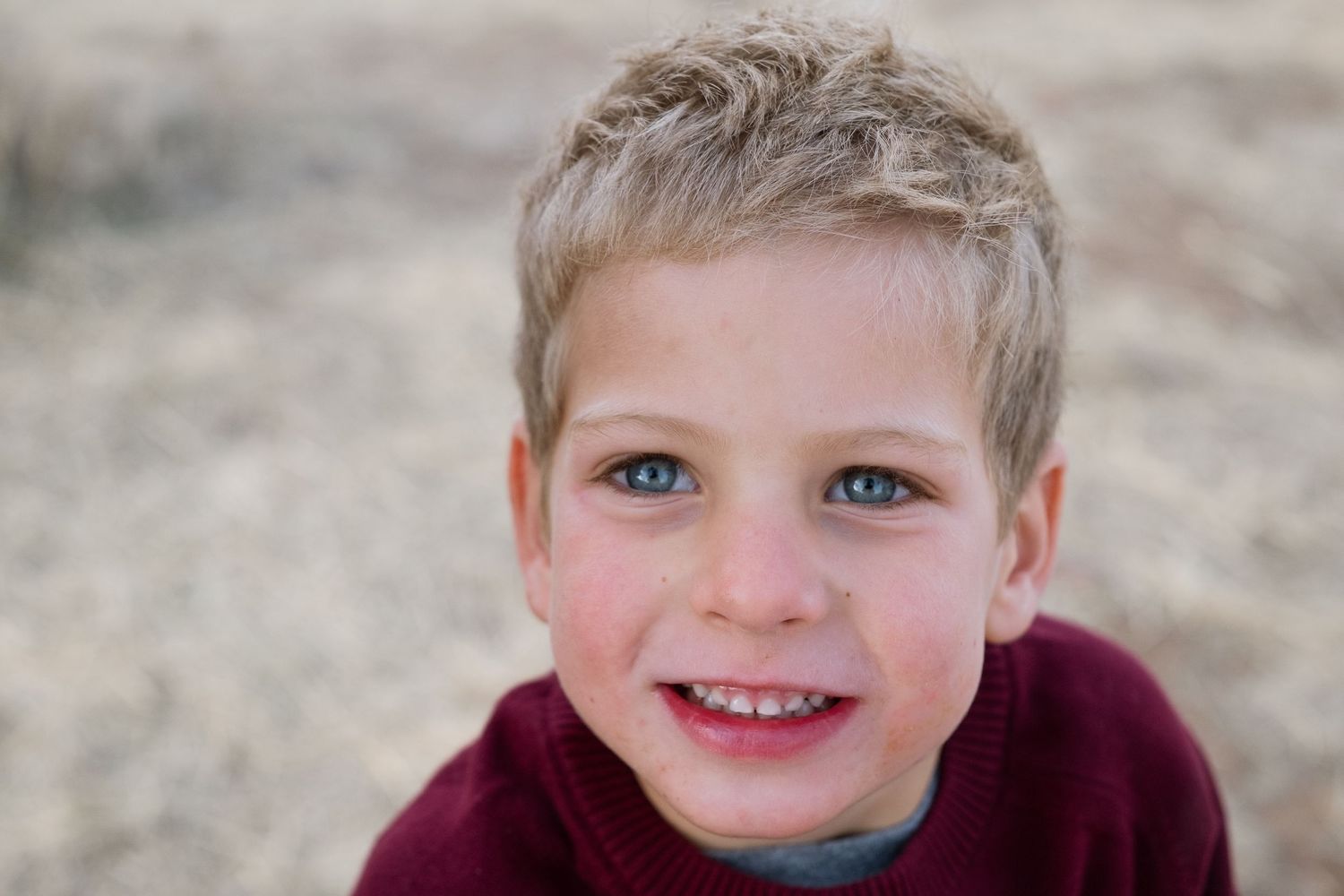 Portrait of blond boy with bright blue eyes, smiling.