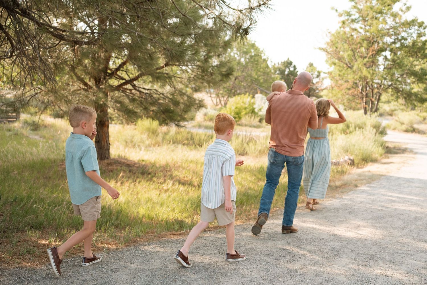 Documentary style photo of family of five walking down dirt path on a summer day at a Denver park.
