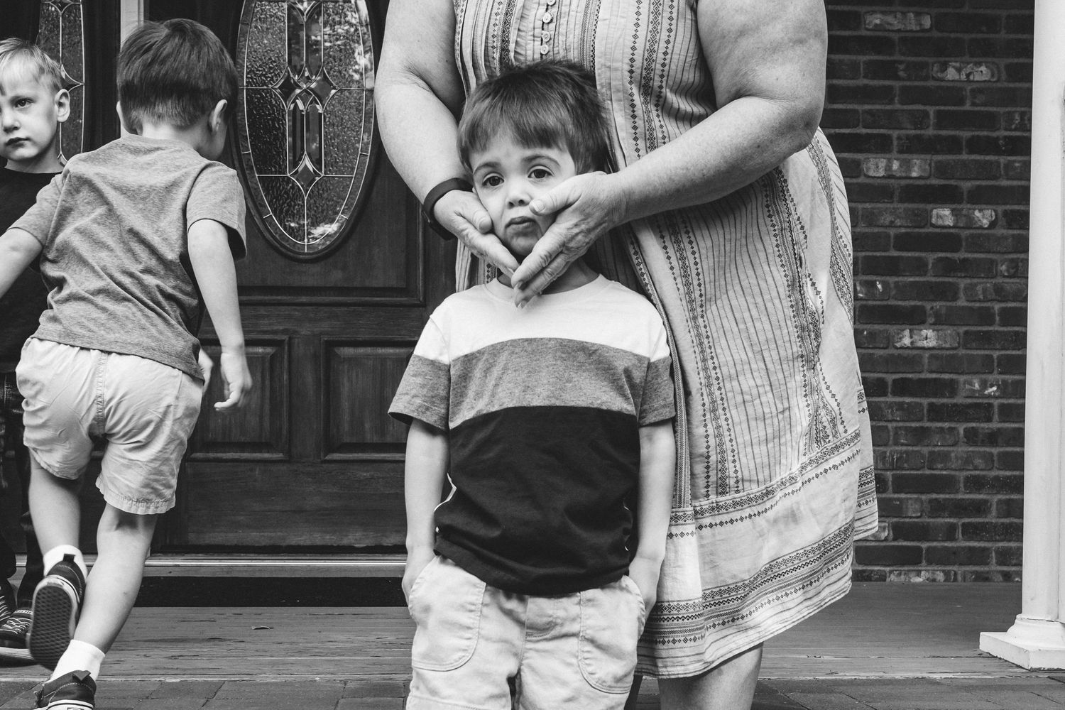 Black and white portrait of grandmother squeezing cheeks of toddler grandson.