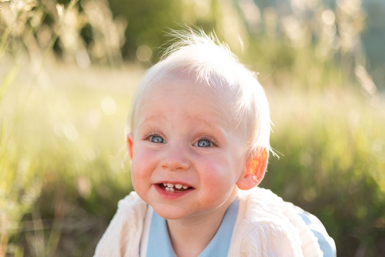 Playful expression on one year old boy, surrounded by tall green grasses at South Valley Park in Littleton, Colorado.