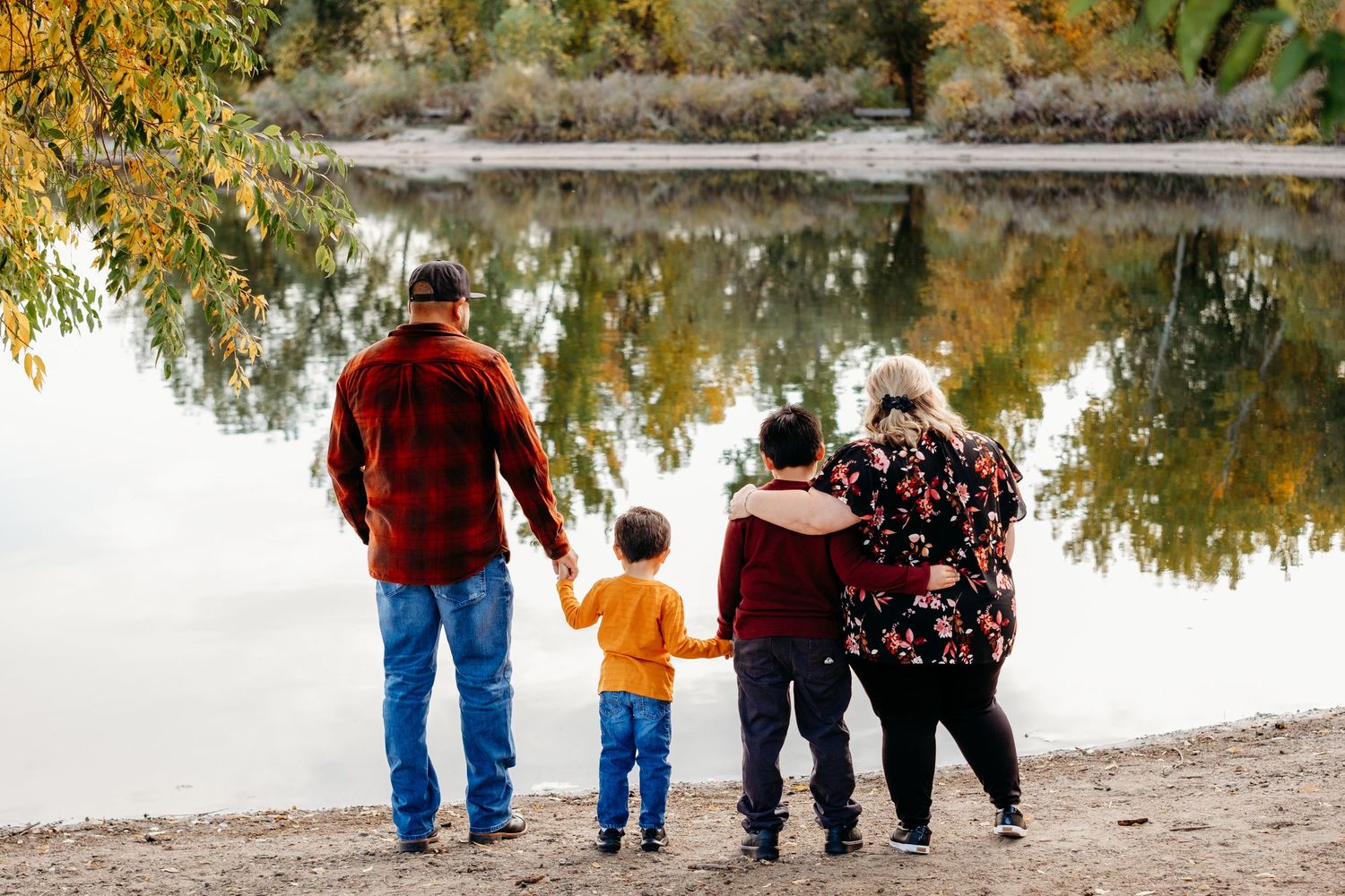 Family of four looking out toward Bear Creek Lake in Lakewood, Colorado.  Reflection of fall trees in the lake.