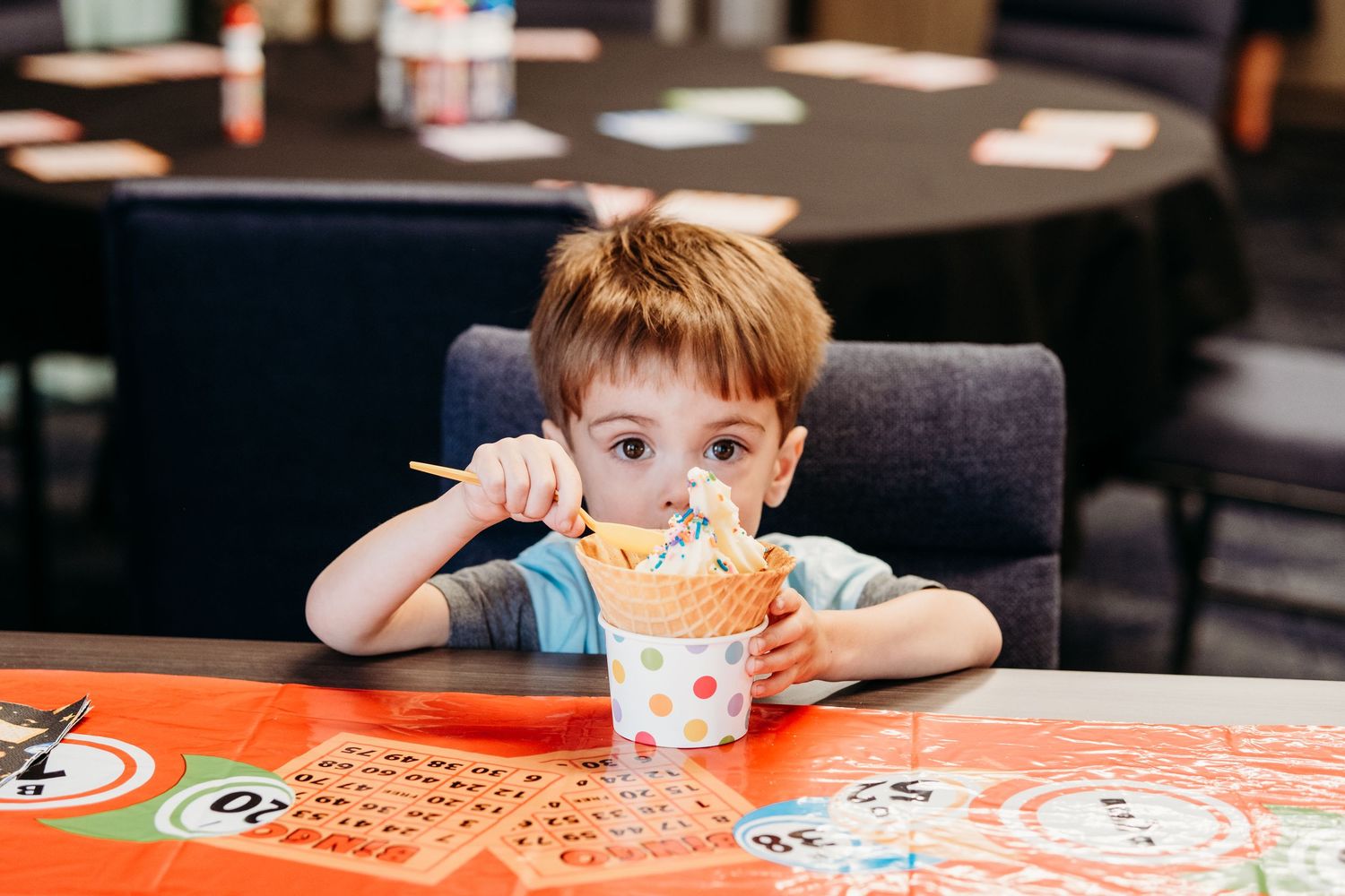 Young boy peering over large ice cream bowl.