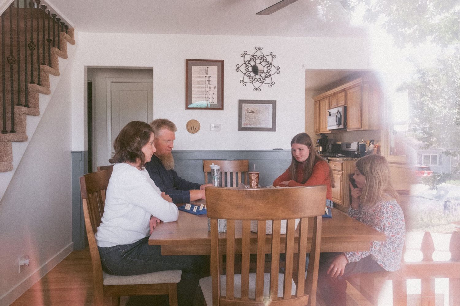 In-home Denver family photography session,  family of four playing rumikub at dining table.