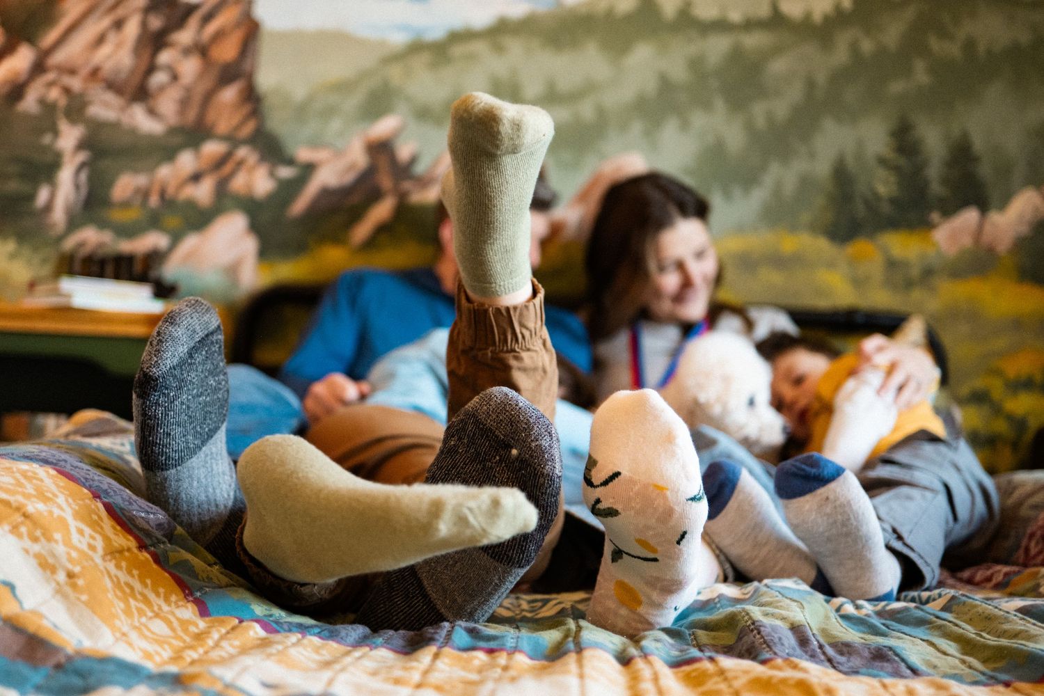 Close up of family socked feet as they all snuggle on the bed during in home, documentary photography session.