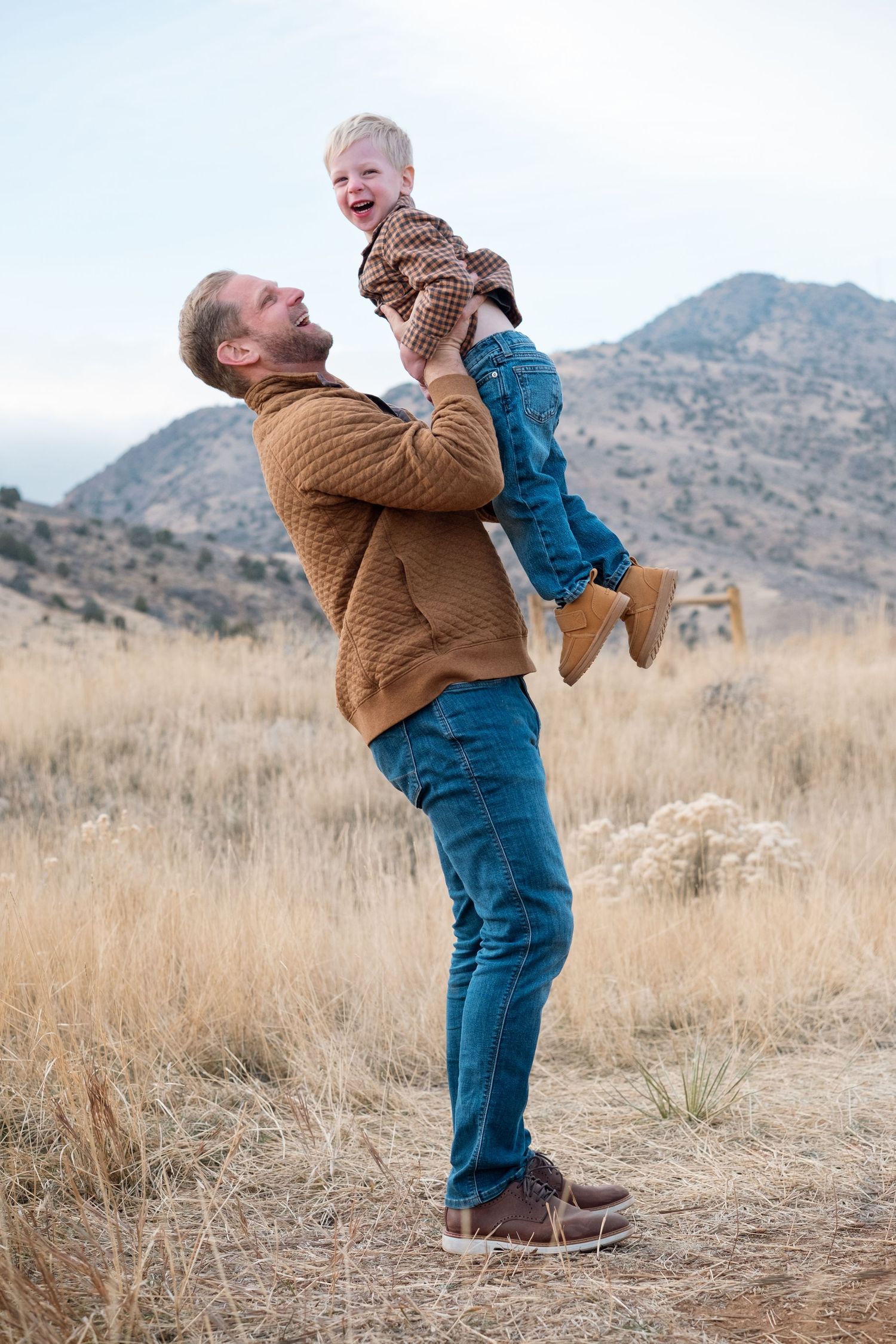 Father playfully tossing his son in the air, son laughing, at Mt Falcon East in Morrison, CO.