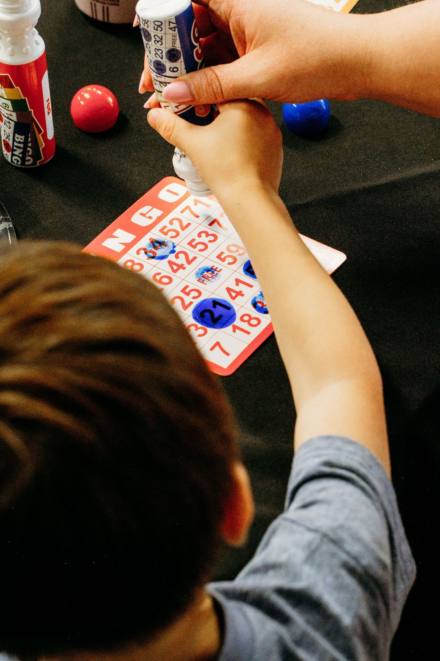 Overhead view of young boys dabbing bingo numbers with bingo markers.