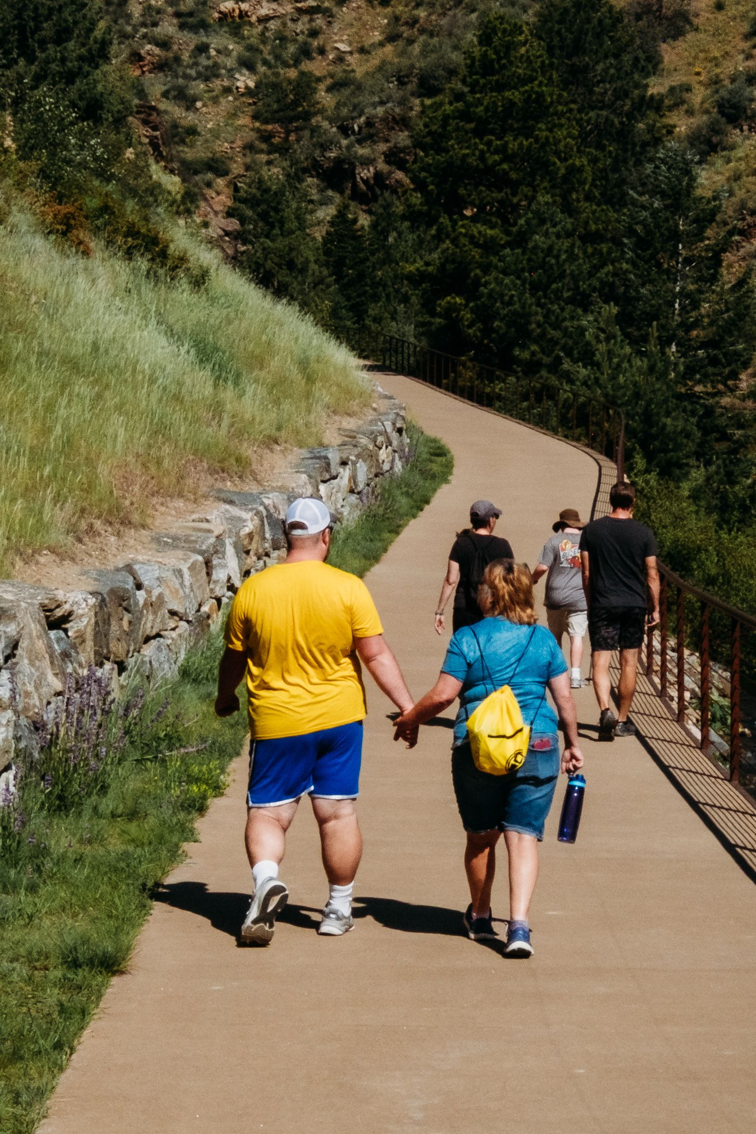 Mother and son walking hand in hand on Clear Creek Trail in Golden, Colorado.
