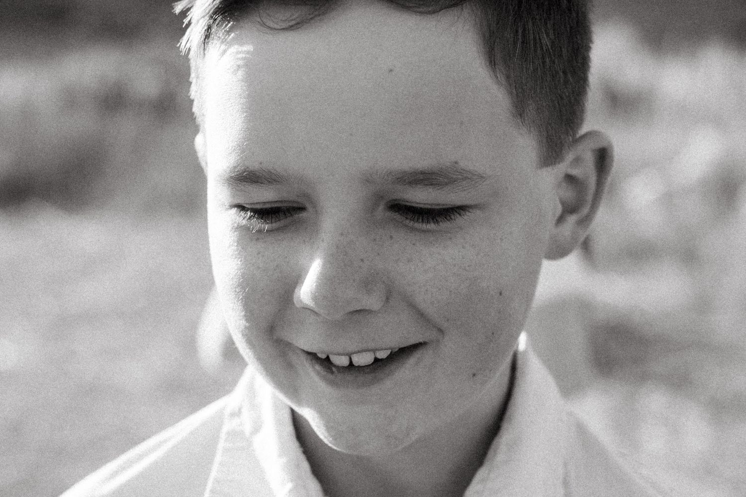 Black and white close up of boy with freckled nose.