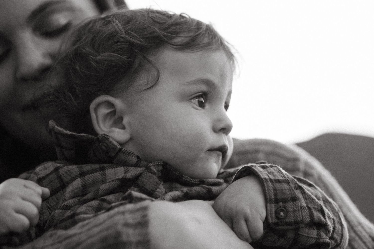 Black and white close up of mother holding one year old son, son looking toward the right thoughtfully.