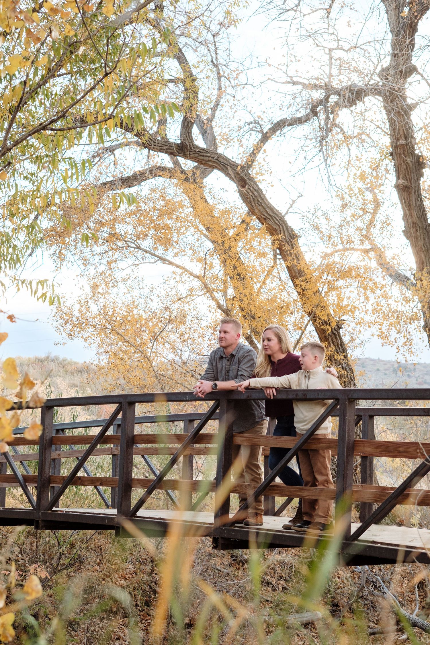 Family portrait on bridge looking down at river with Documentary Lakewood Family Photographer.