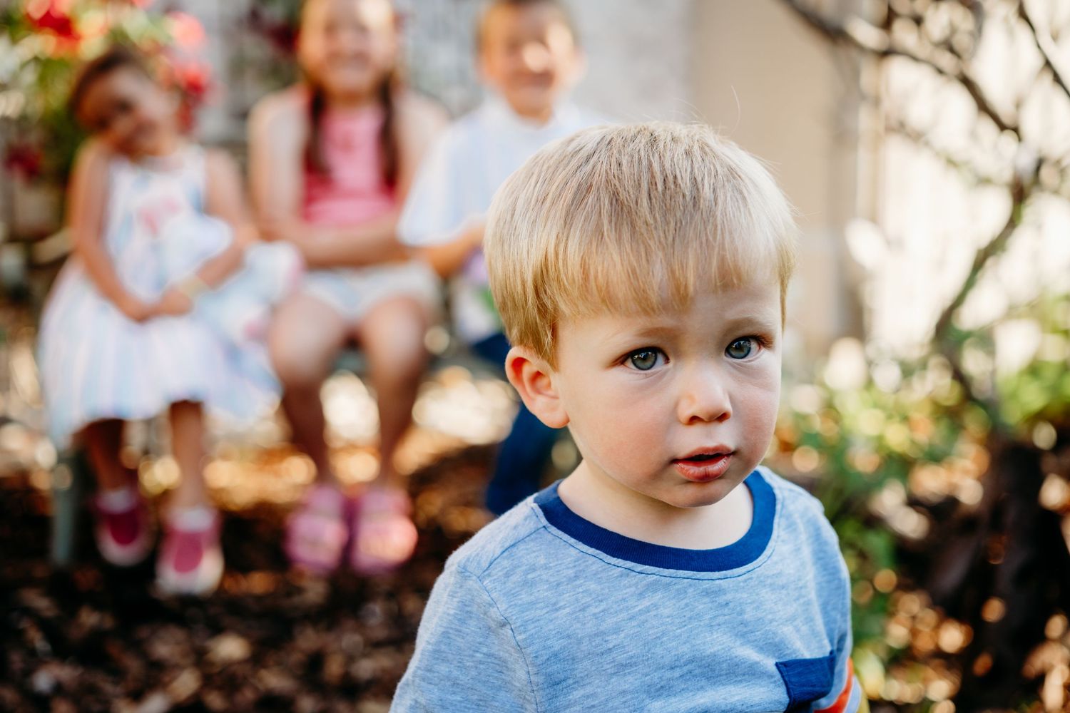 Young boy walking toward camera, three cousins blurred in background.