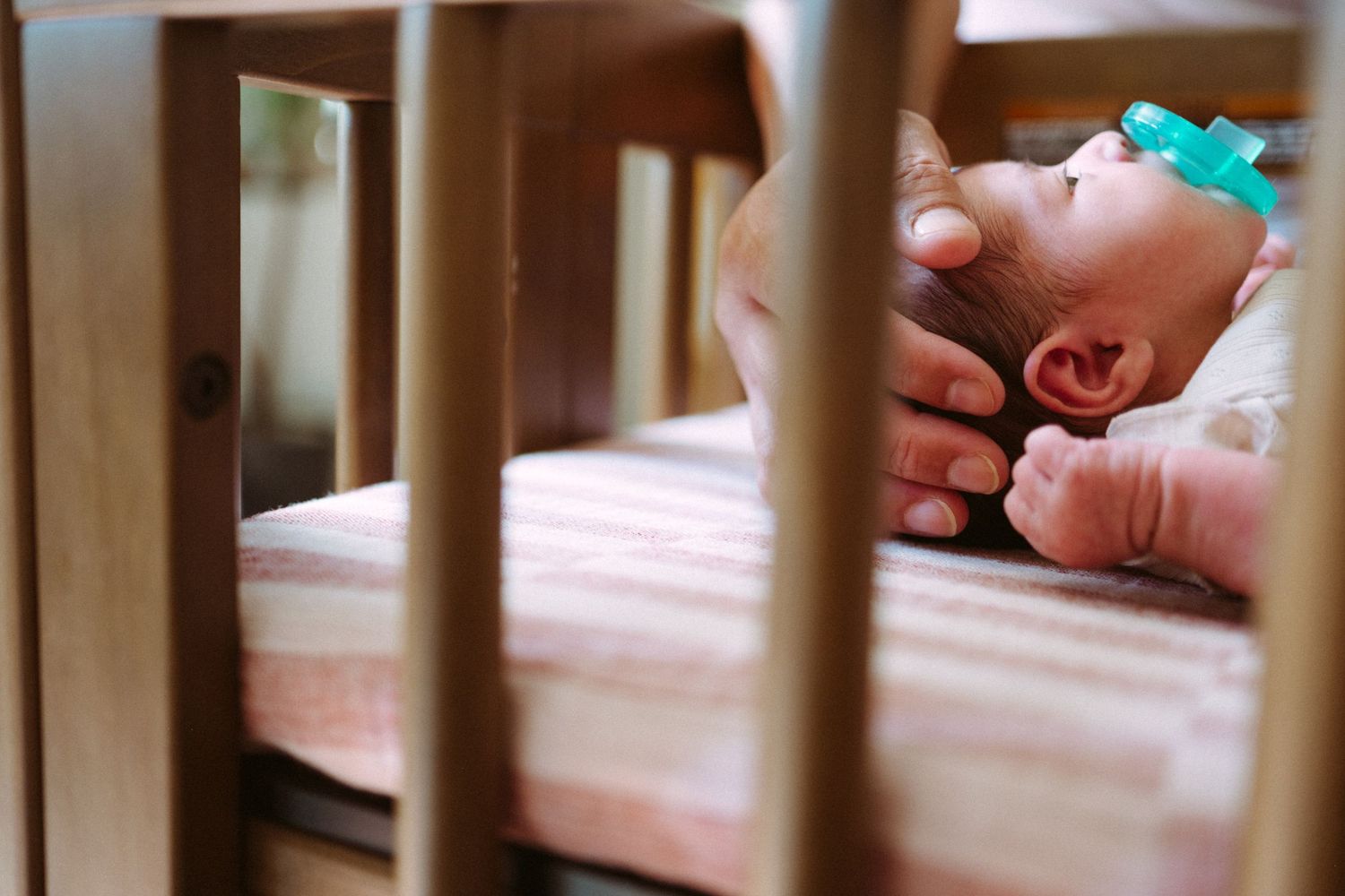 Close up of baby as she lies in a beautiful wood crib.