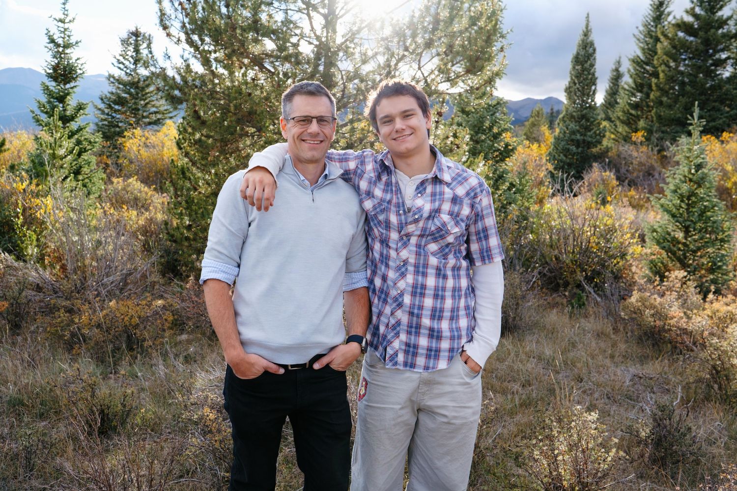 Father and son standing together in Colorado mountains.