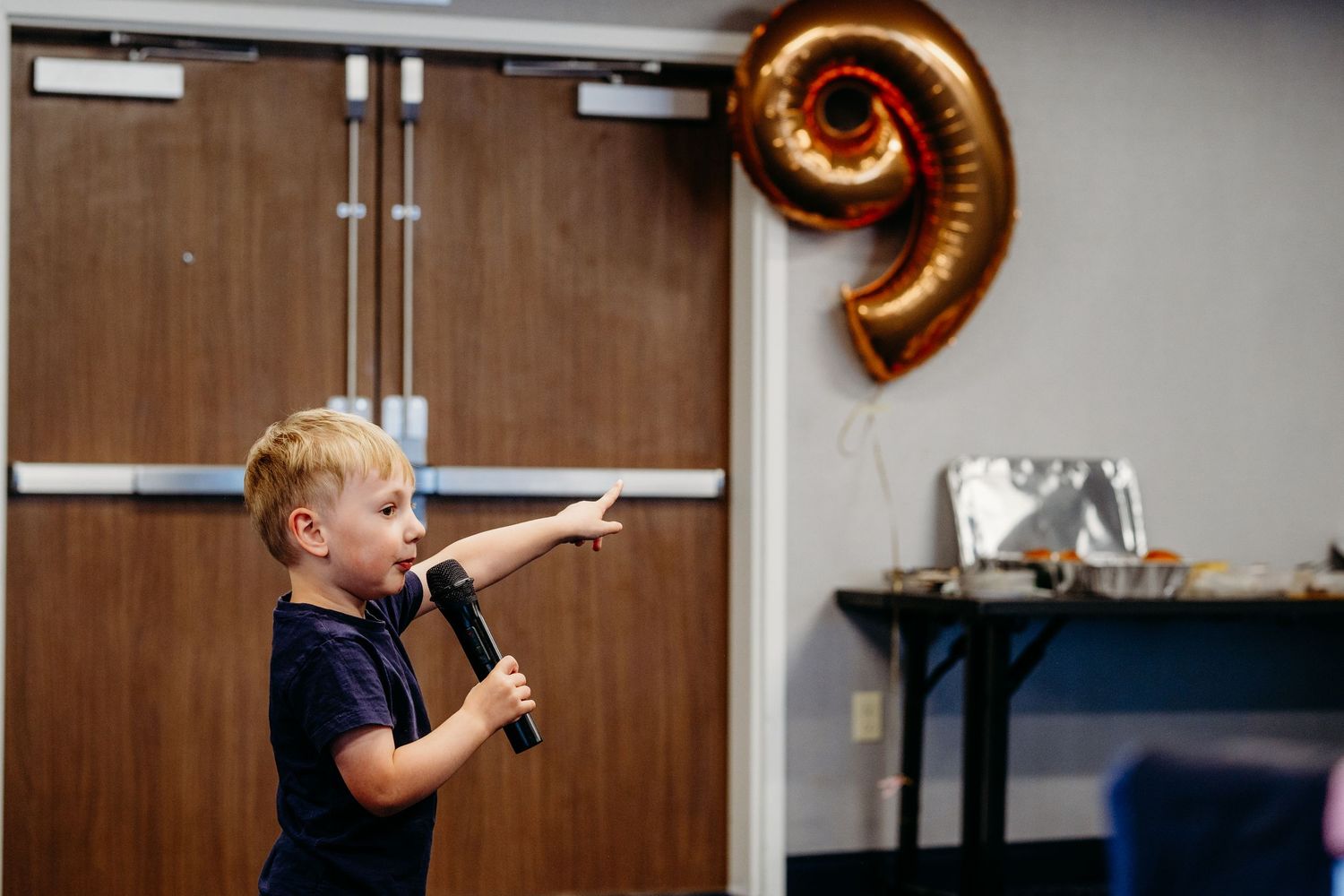 Young boy pointing to 9 balloon on hotel wall.