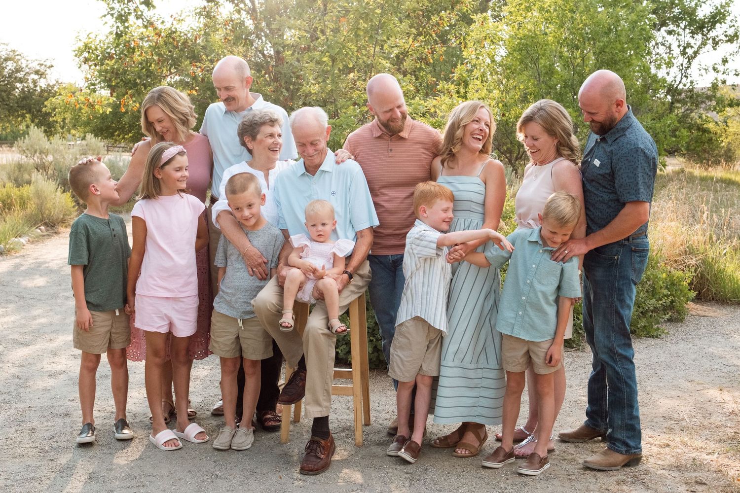 Candid of multigeneration family of forrteen during extended family photo session, everyone looking toward one another.