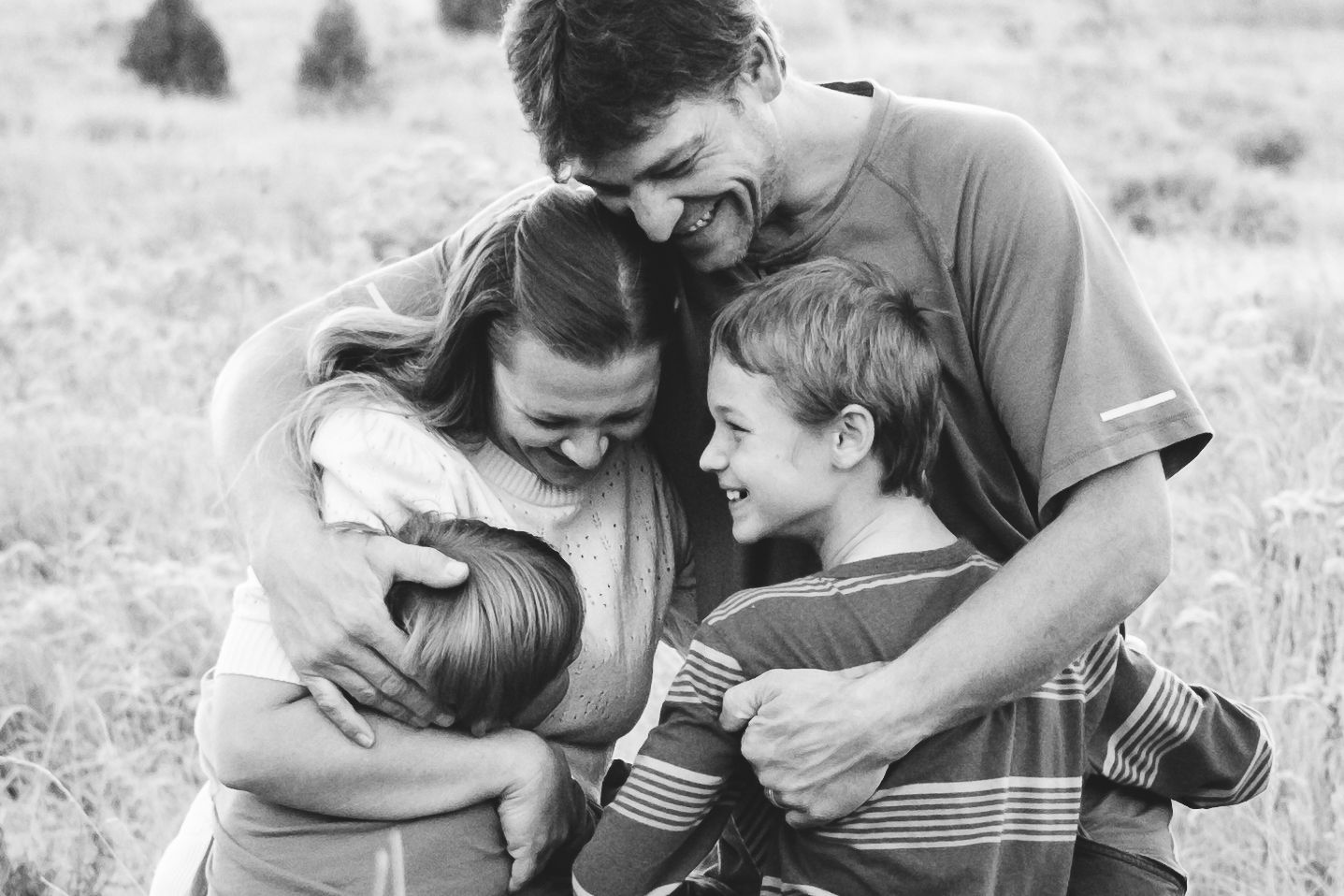 Black and white portrait of family of four embracing one another at Matthews / Winters Park in Golden, CO.