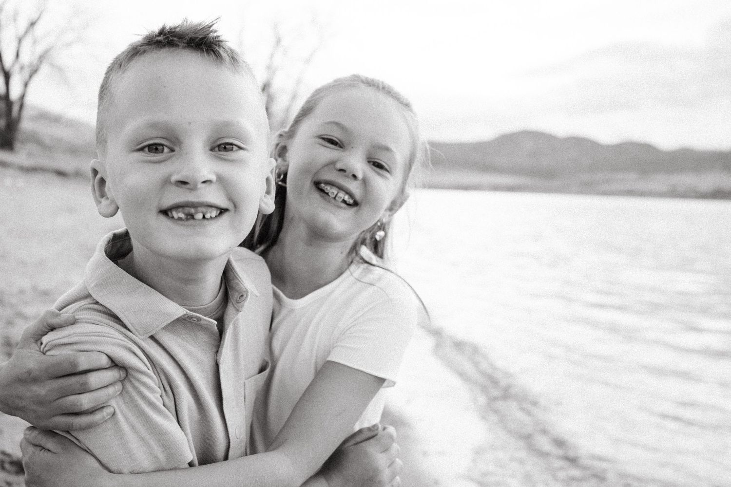 Family photo session at Chatfield State Park, black and white smiling portrait of  brother and sister hugging.