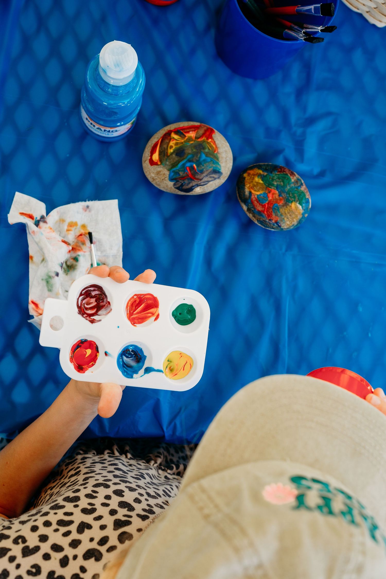 Denver photographer's project 365, June, overhead view of child painting a rock with vibrant paint colors.