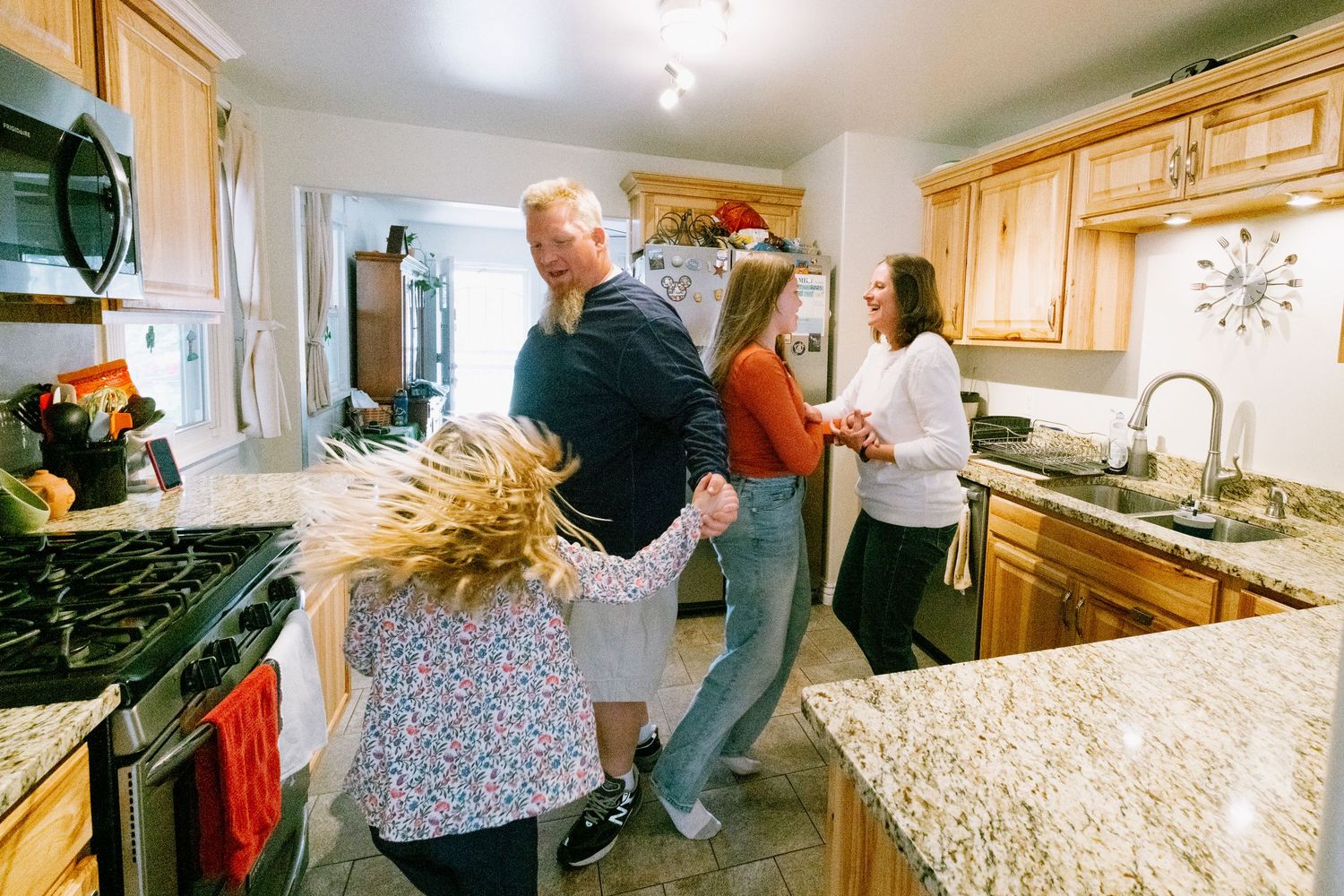 Denver family having a playful dance party in kitchen.