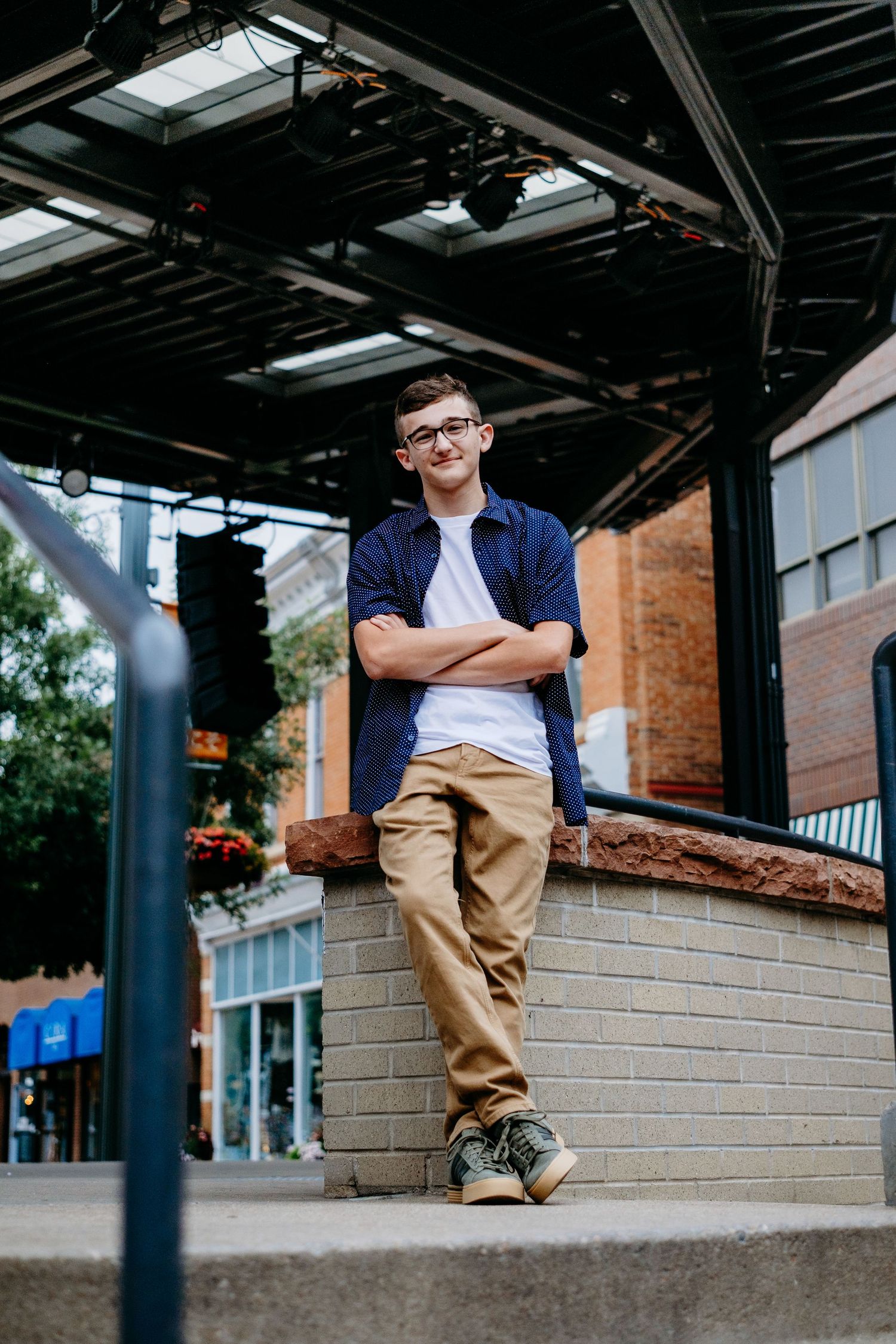 Senior portrait of a teenage boy in downtown Fort Collins, sitting at amphitheatre. Captured by a Denver senior photographer,