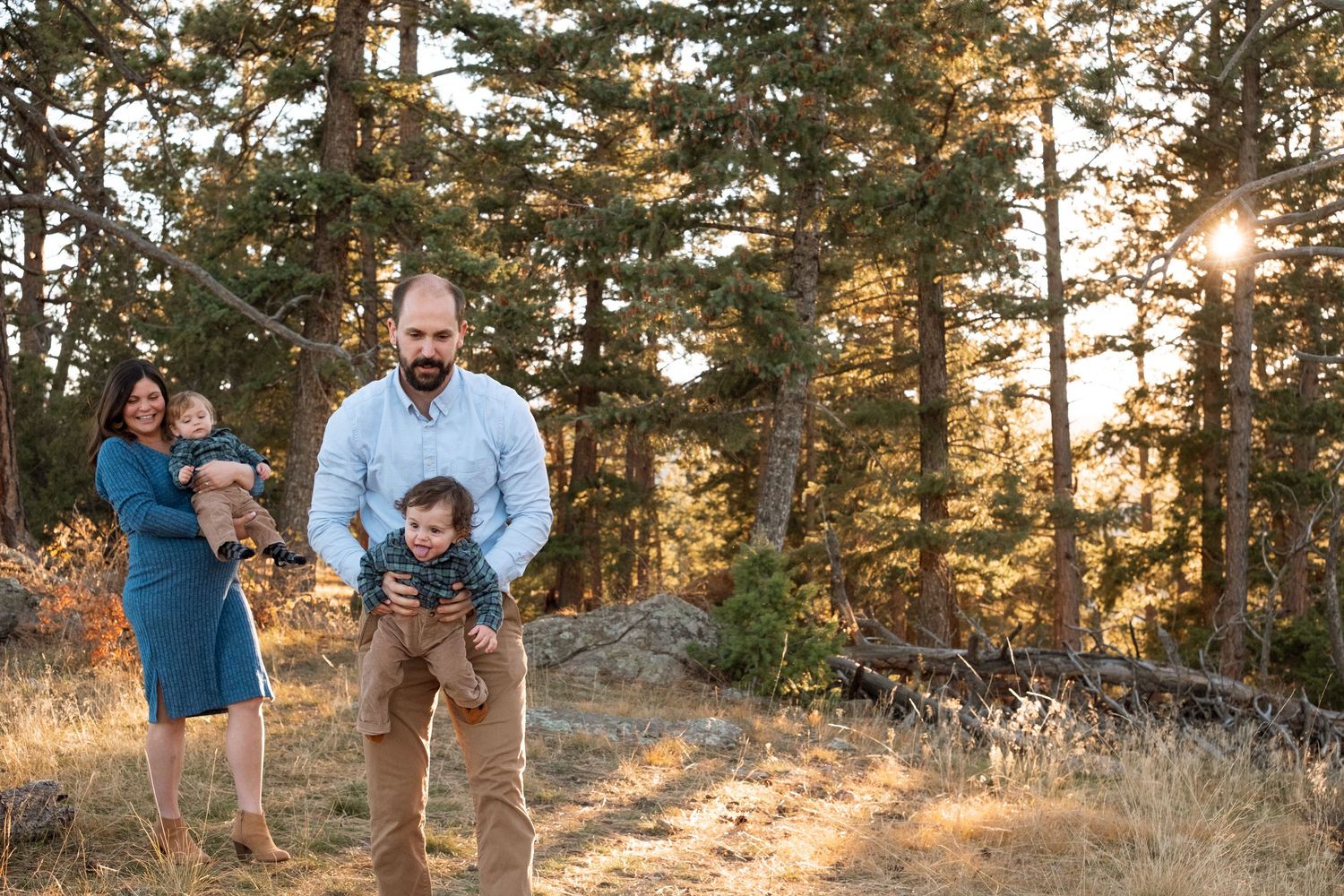 Playful documentary portrait of father holding one twin, mother holding the other, walking in the trees at Mt Falcon West.