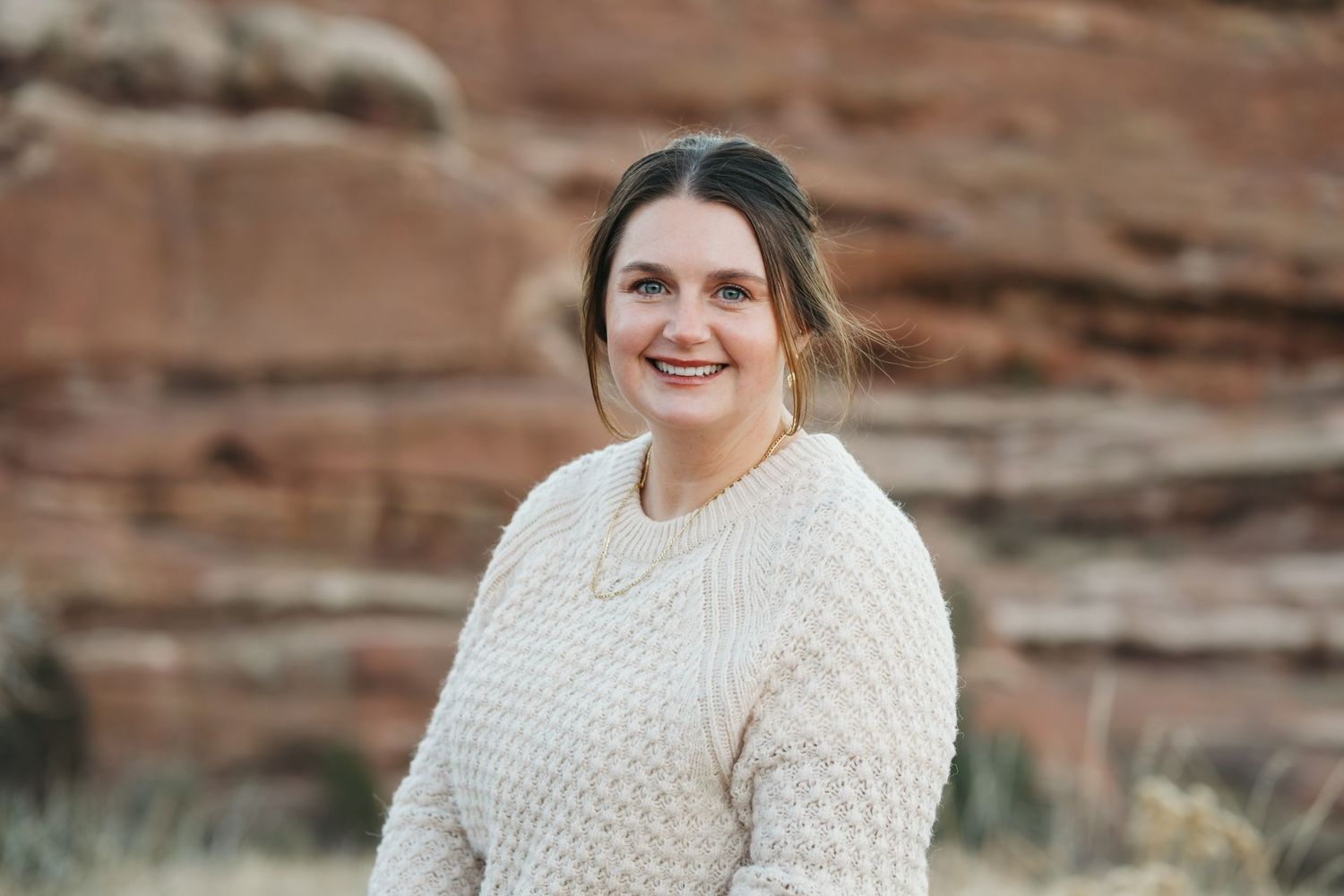 Branding headshot of female lawyer in Red Rocks Park, Morrison, Colorado with rock formation in background.