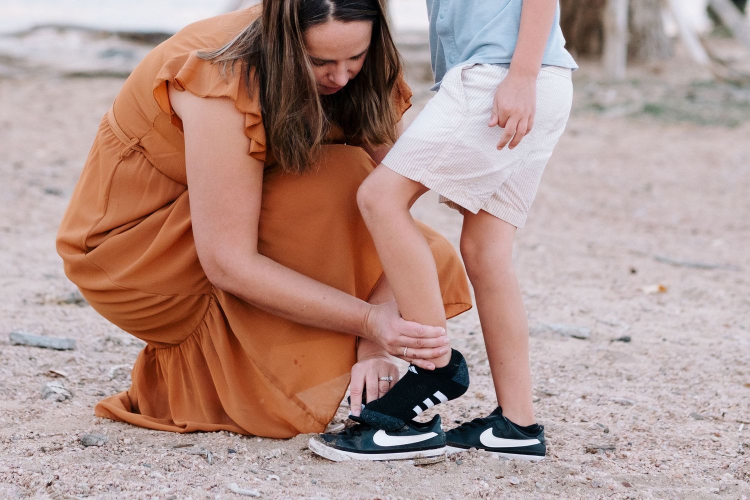 Mother fixing shoe for young son.