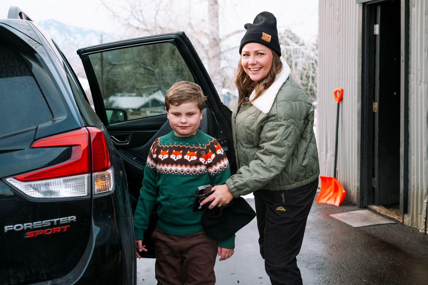 Documentary photograph of mother and son getting out of car, dressed in warm winter gear, preparing for sledding.