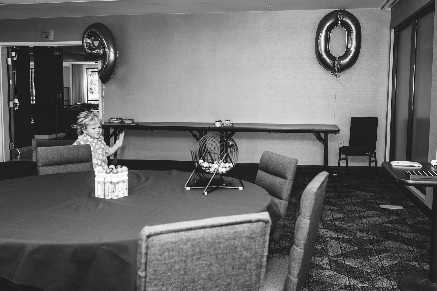 Young boy running in hotel hall decorated for his great grandma's 90th birthday party.