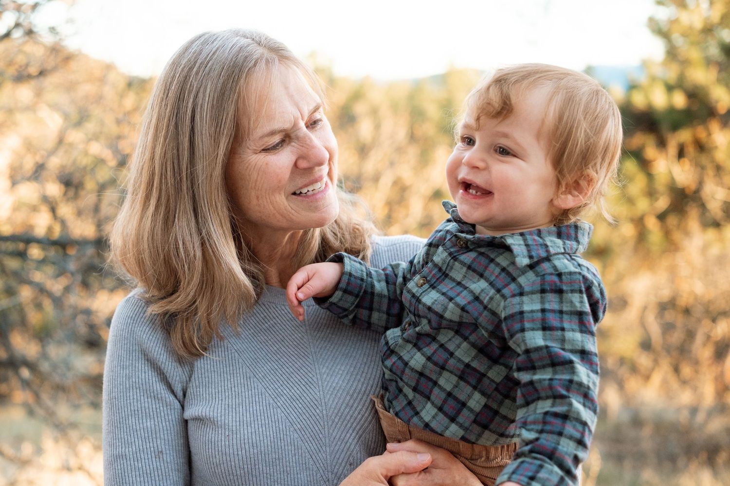 Grandmother holding one year old grandson, both smiling.