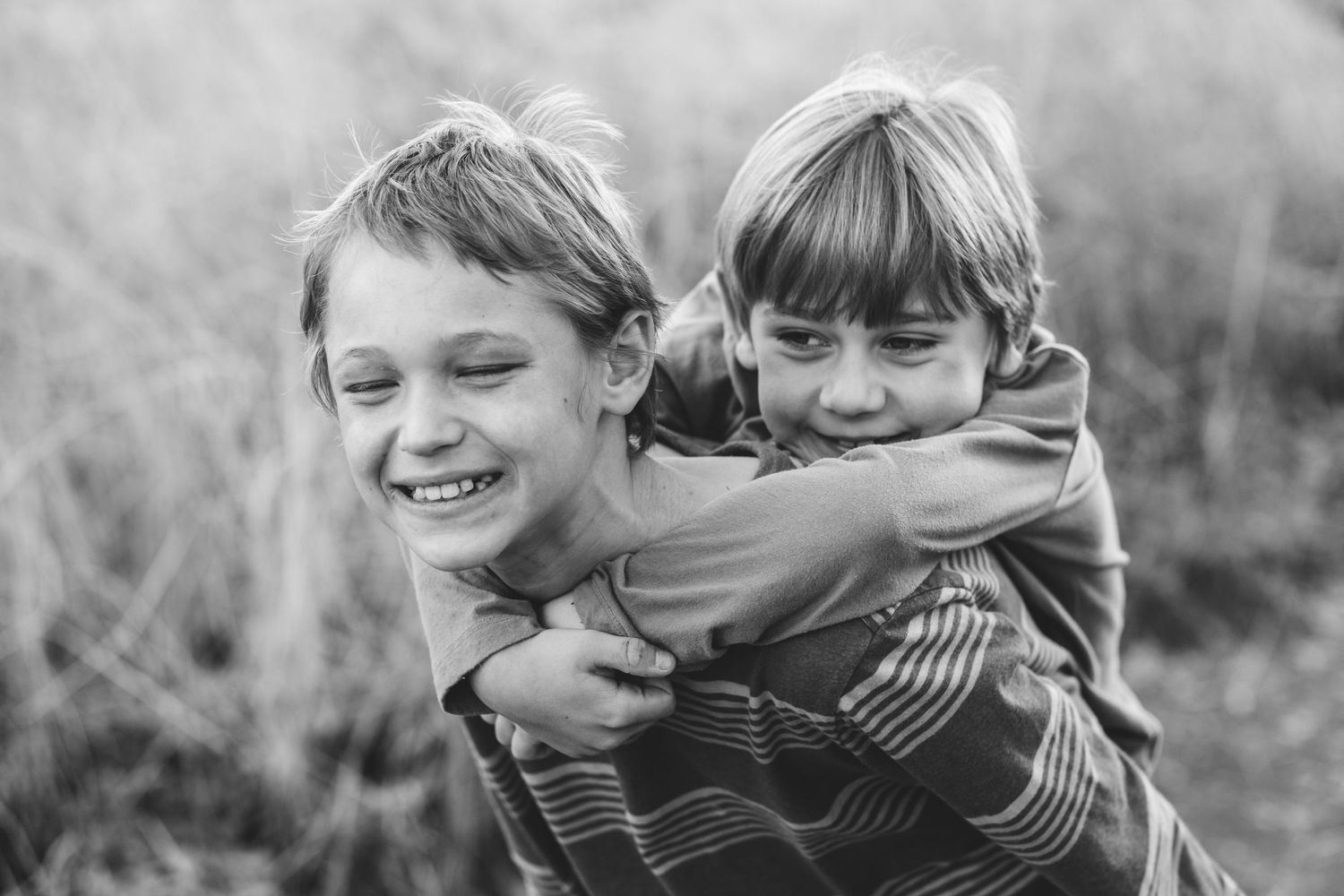 Black and white portrait of brother giving younger brother a piggy back ride.