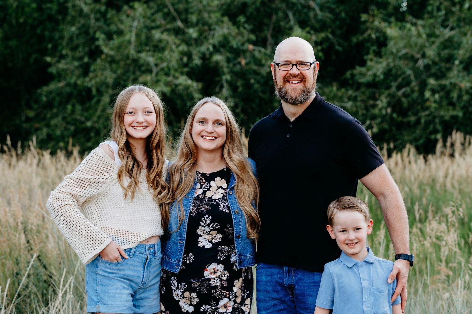 Family of four portrait, all smiling at the camera, at Hildebrand Park in Littleton, Colorado.