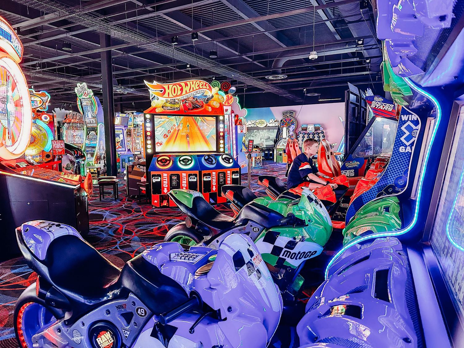 Vibrant photo of an arcade, lots of purple motorcycle racing games.