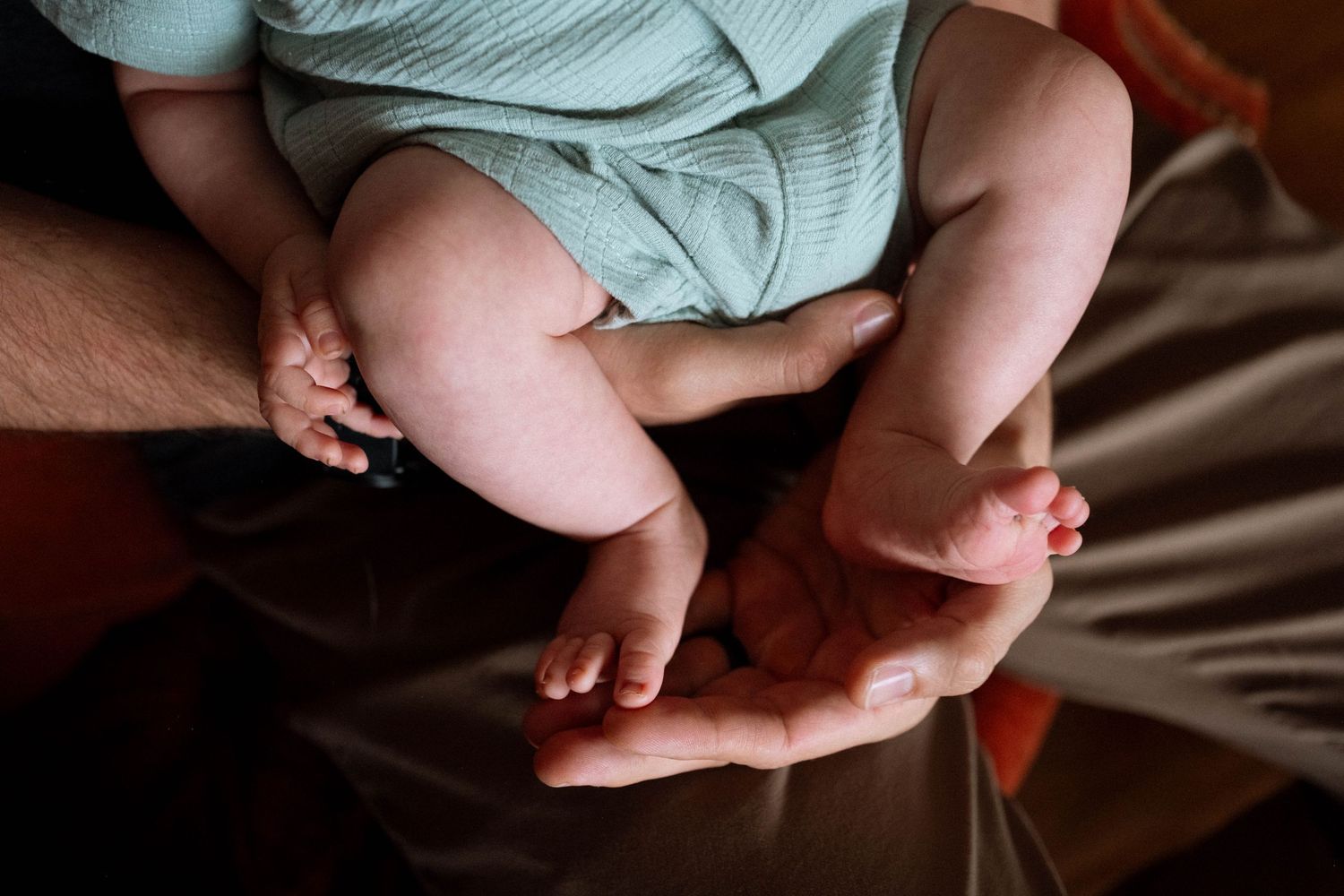 Close up baby portrait of father holding baby's feet.