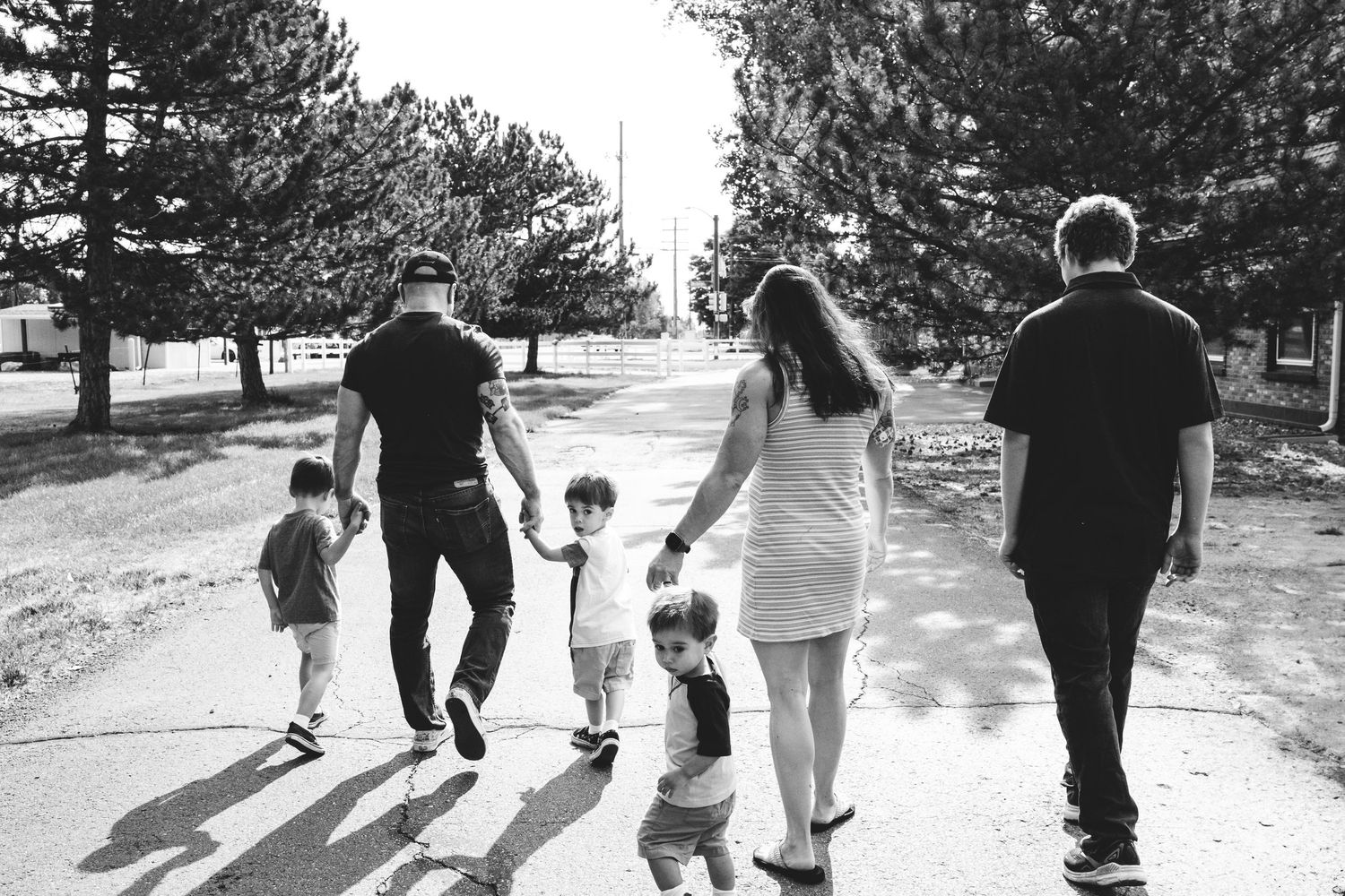 Black and white portrait of mother and father walking on path with four sons on family property in Golden, Colorado.