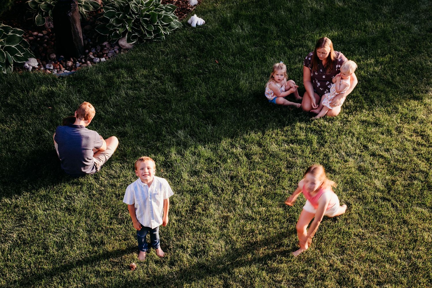 Documentary photo of children running in playground, aunts and uncles sitting nearby.