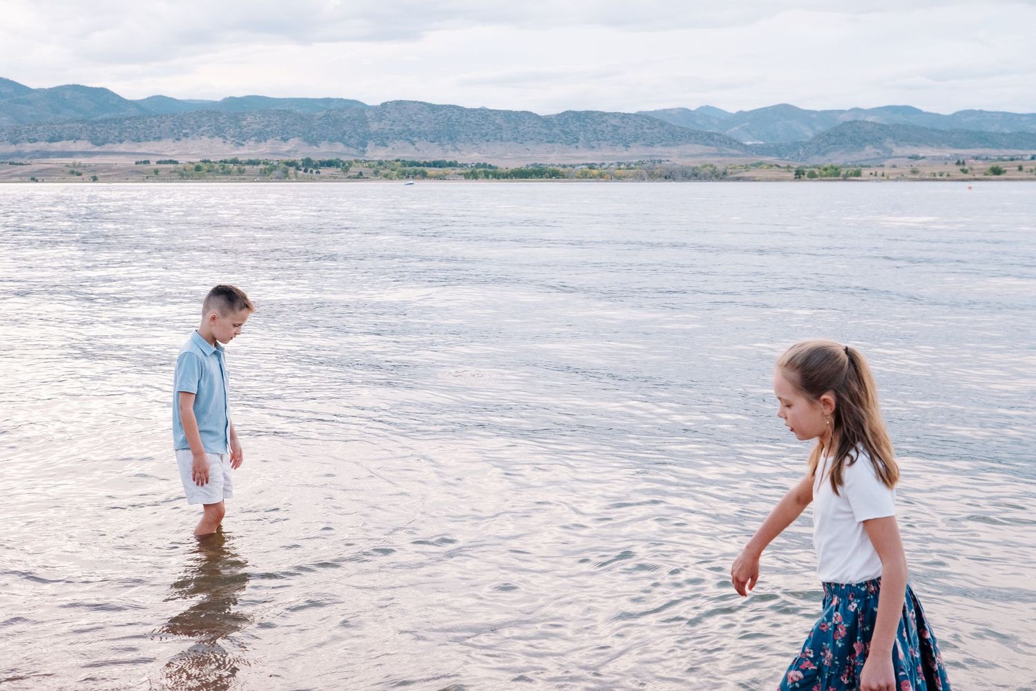 Brother and sister wading in water at Chatfield State Park.