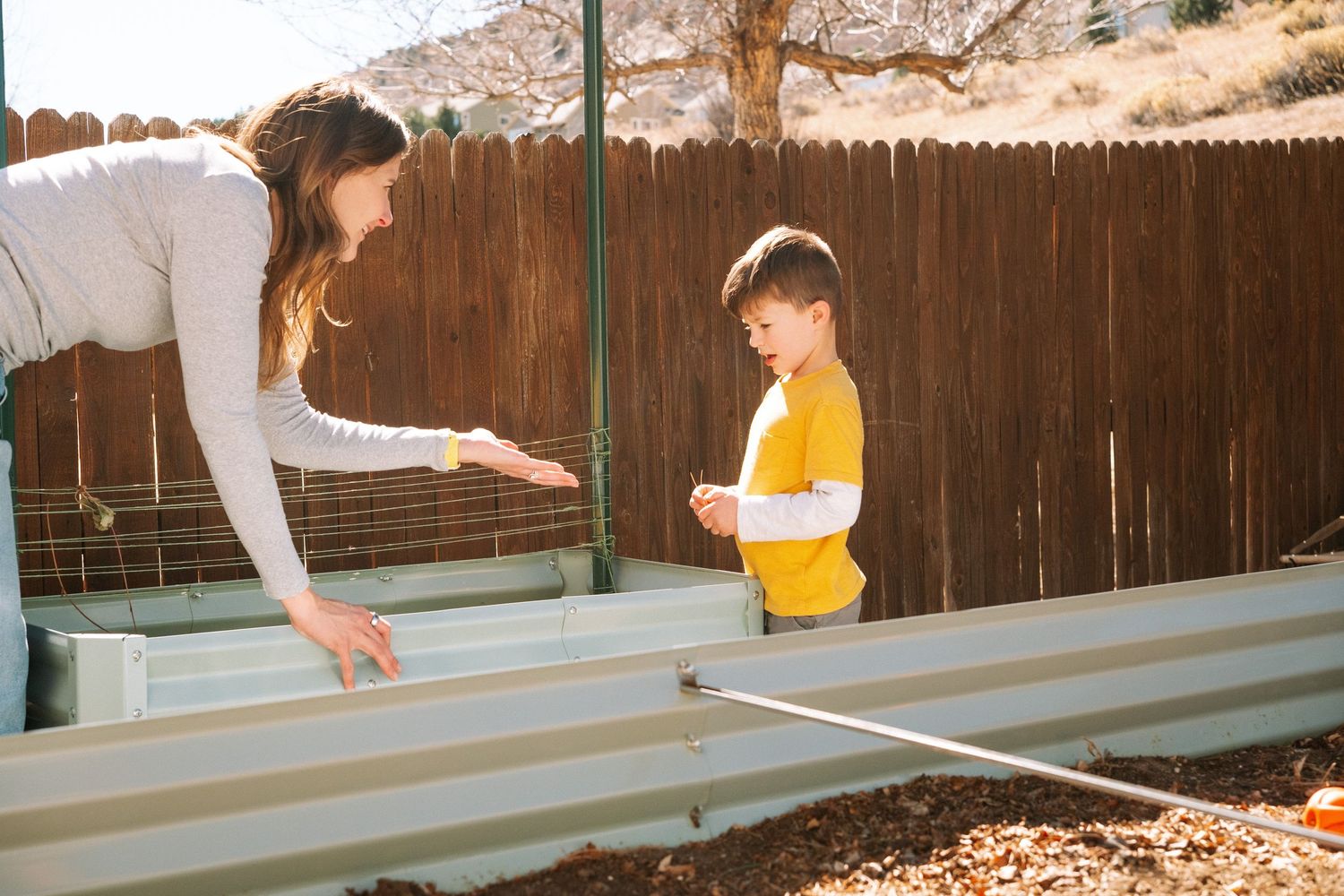 Mother showing son a worm in backyard garden.